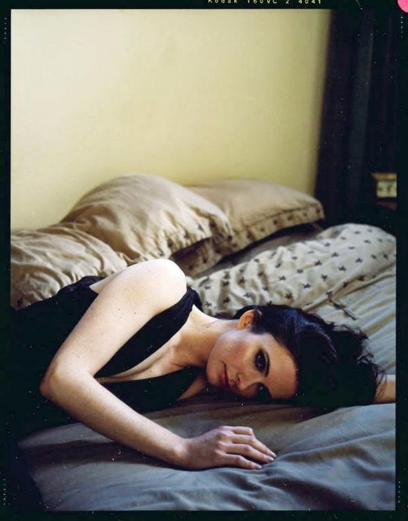 Bitsie Tulloch lays on bed squeezing her melons